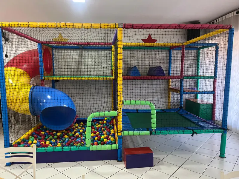 Playground de vários andares com tobogã, piscina de bolinhas e cama elástica, todo protegido por rede