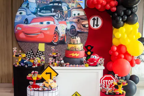 Tema Carros: painel redondo com o Relâmpago McQueen, bolo de pneu, placa de pare e balões vermelhos, amarelos e pretos
